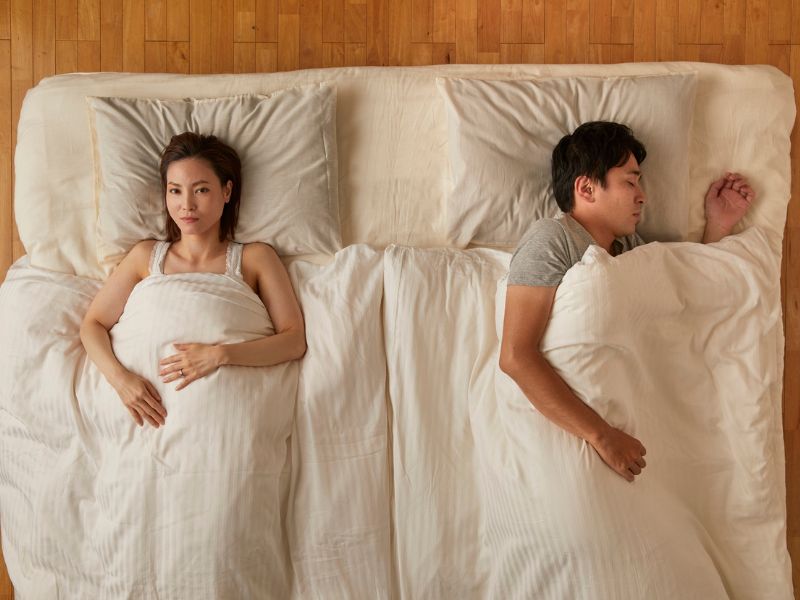 Ein Paar liegt getrennt im Bett und hat in ihrer langen Beziehung weniger Sex